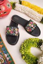 Stepellas black handmade flat chappals featuring vibrant pink and yellow floral hand-embroidery.