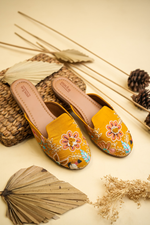 Stepellas mustard yellow juttis featuring vibrant 3D floral embroidery and colorful leaf threadwork.