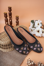 Stylish Stepellas branded black flat mules displayed on an aesthetic peach background.
