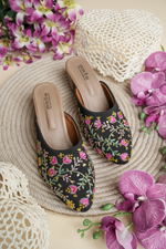 Stepellas black mojdis with white line-art embroidery and colorful leaf motifs.