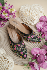 Traditional Stepellas black juttis featuring pink and yellow floral vine embroidery.