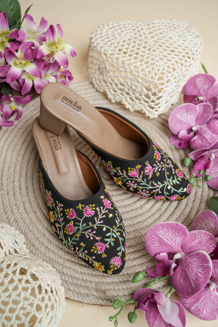 Traditional Stepellas black juttis featuring pink and yellow floral vine embroidery.