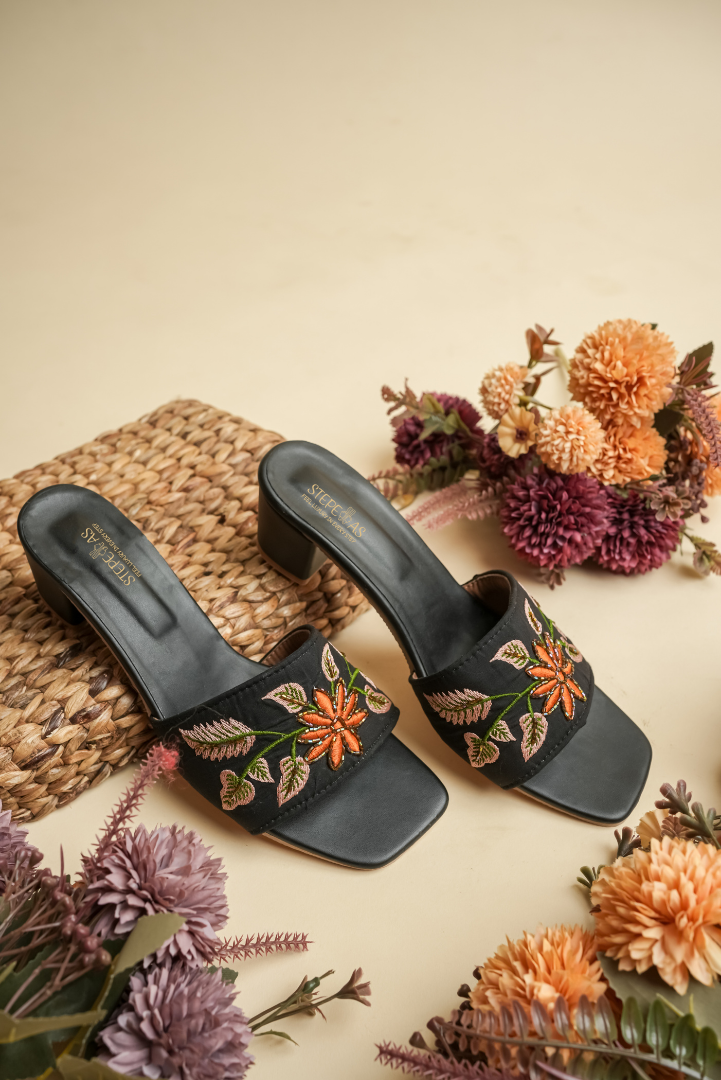 Stepellas black block heels featuring a detailed orange flower and pink leaf embroidery design.