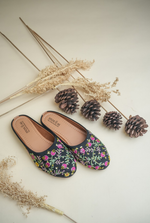Stepellas black ethnic juttis featuring vibrant pink and yellow floral embroidery with green vine work.