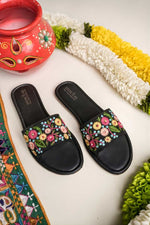 Detailed close-up of the dense multi-color floral hand-embroidery on Stepellas black ethnic sandals.