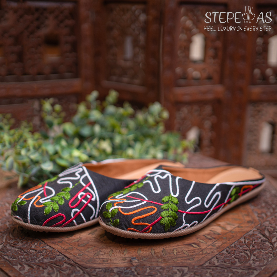 Handcrafted Stepellas black juttis with square Siroski stone patterns and beige floral motifs.