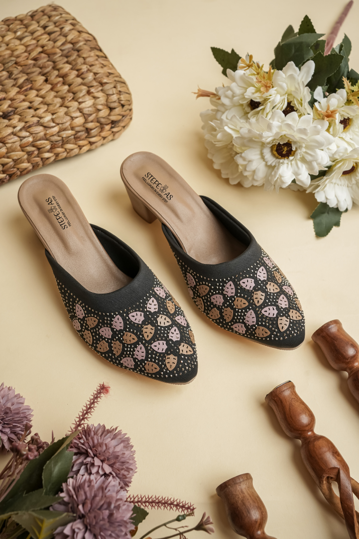 Black Stepellas heeled mules featuring rose-gold leaf-shaped stud patterns and a comfortable block heel.
