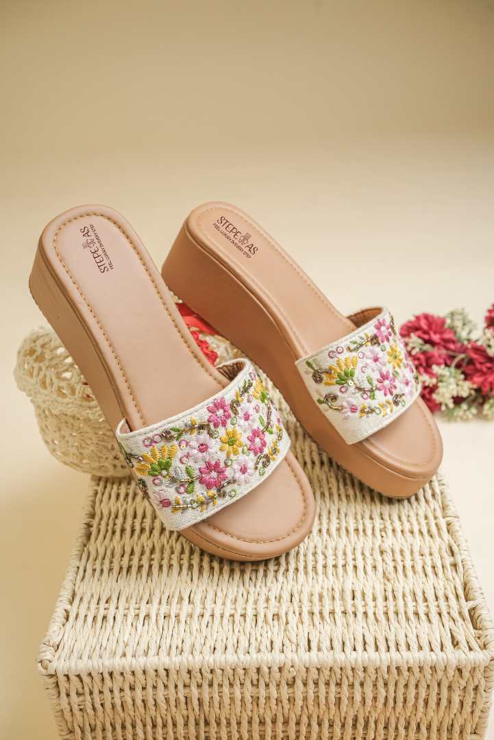 Stepellas brown handcrafted juttis featuring vibrant magenta and yellow floral vine embroidery.