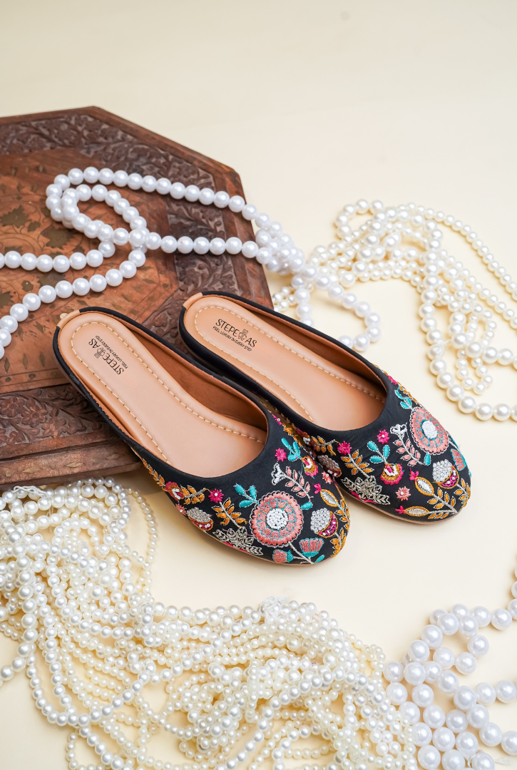 Top view of Stepellas branded black hand-embroidered juttis highlighting the soft, padded tan insole.