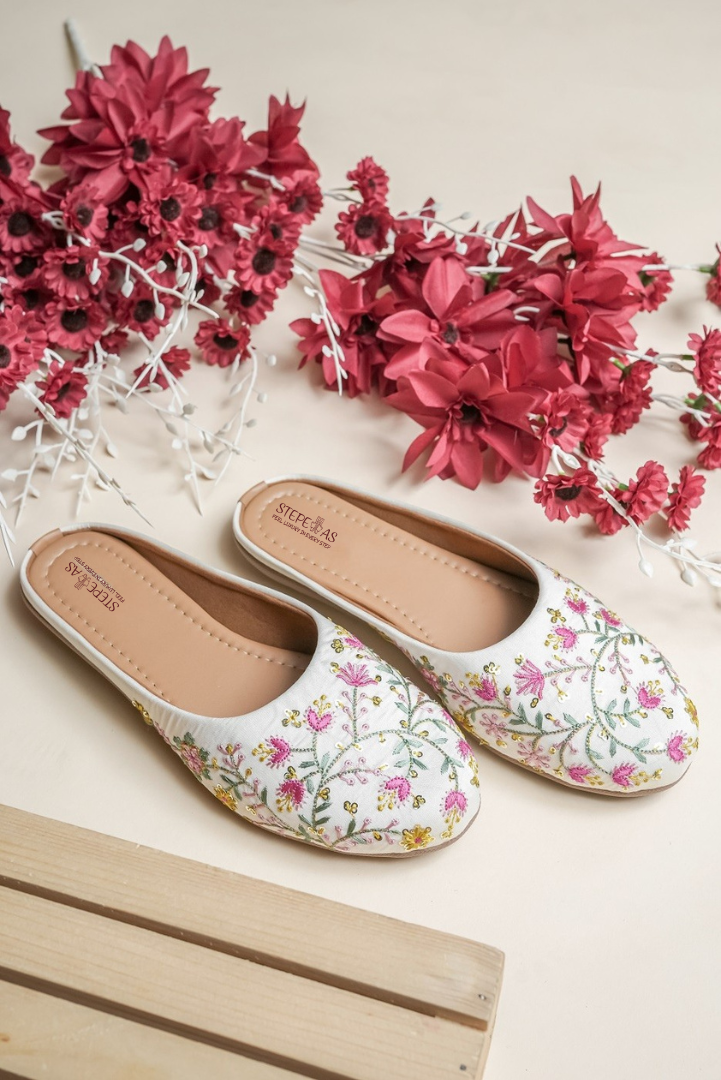 Top view of Stepellas branded white floral juttis highlighting the soft cushioned tan insole for comfort.