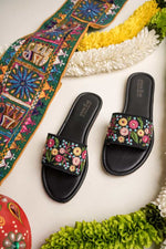 Elegant Stepellas black floral chappals displayed with traditional marigold garlands for a festive aesthetic.