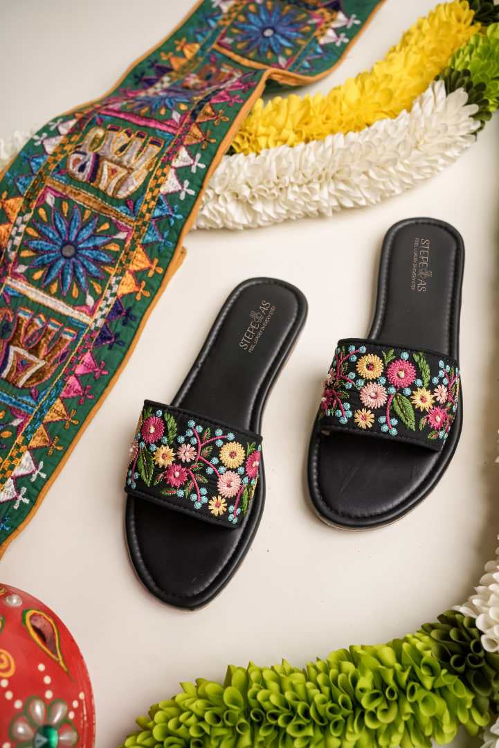 Elegant Stepellas black floral chappals displayed with traditional marigold garlands for a festive aesthetic.