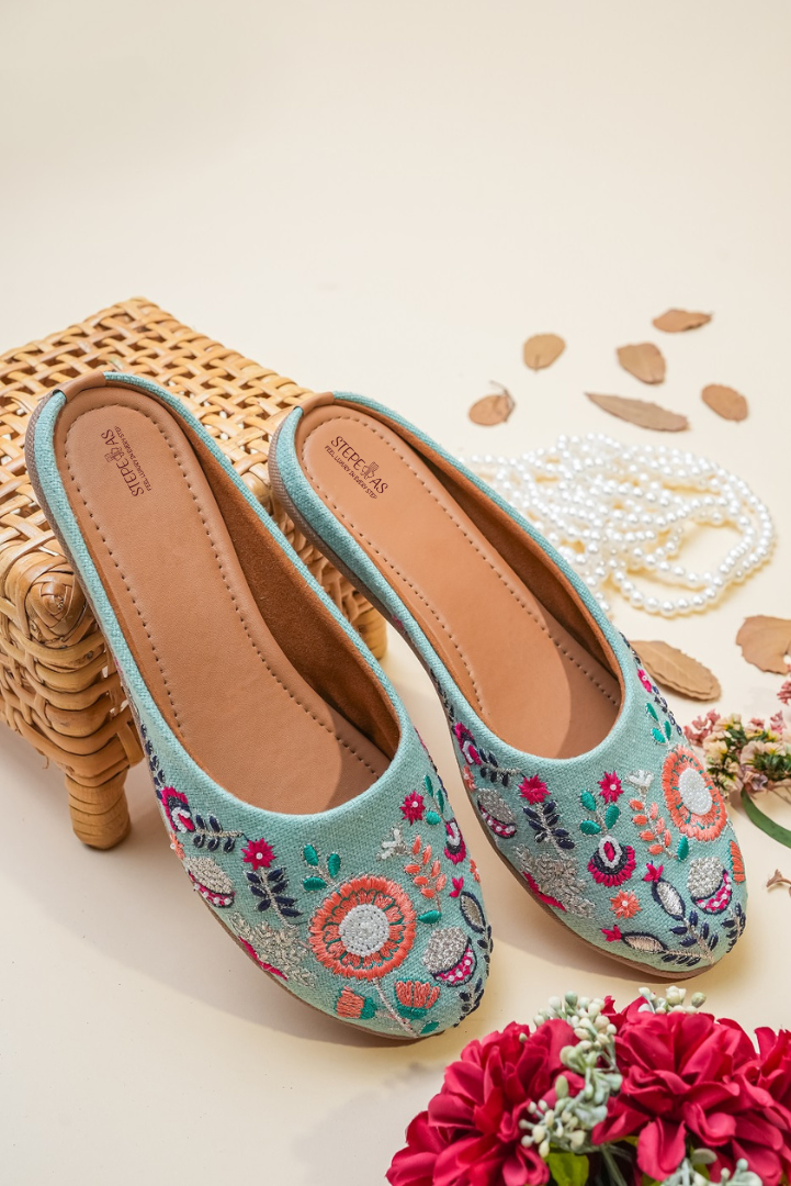 Elegant Stepellas sky blue juttis displayed with pearls and floral decor for a traditional wedding aesthetic.