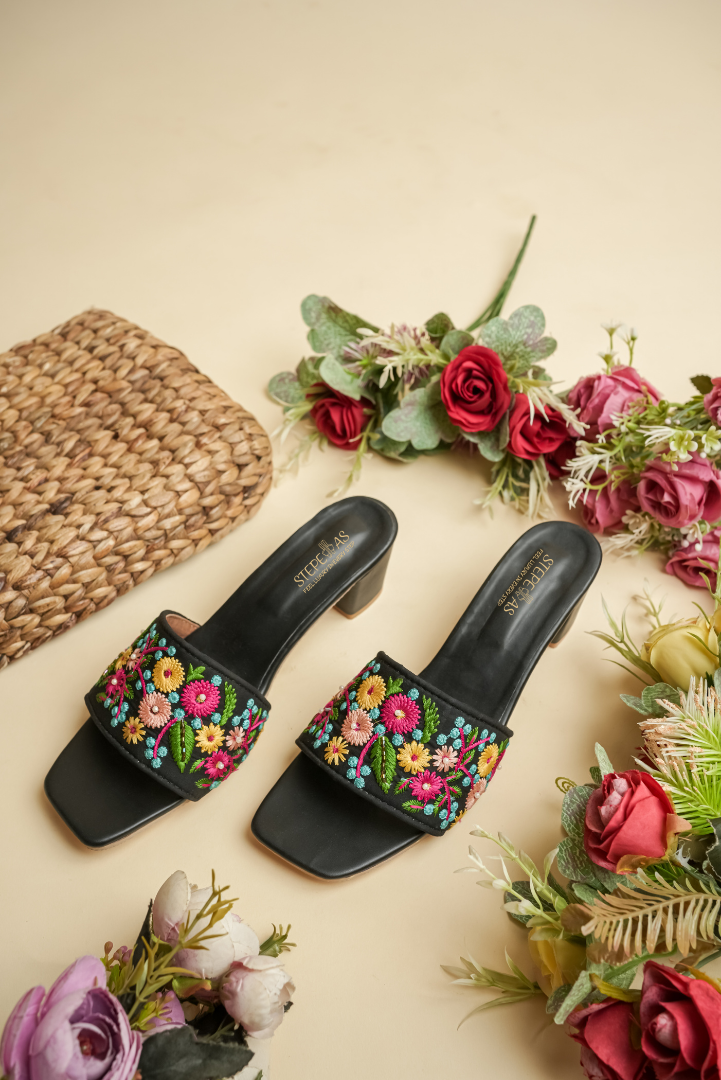 Side view of Stepellas black ethnic heeled mules showing the detailed multi-color threadwork and stable block heel.