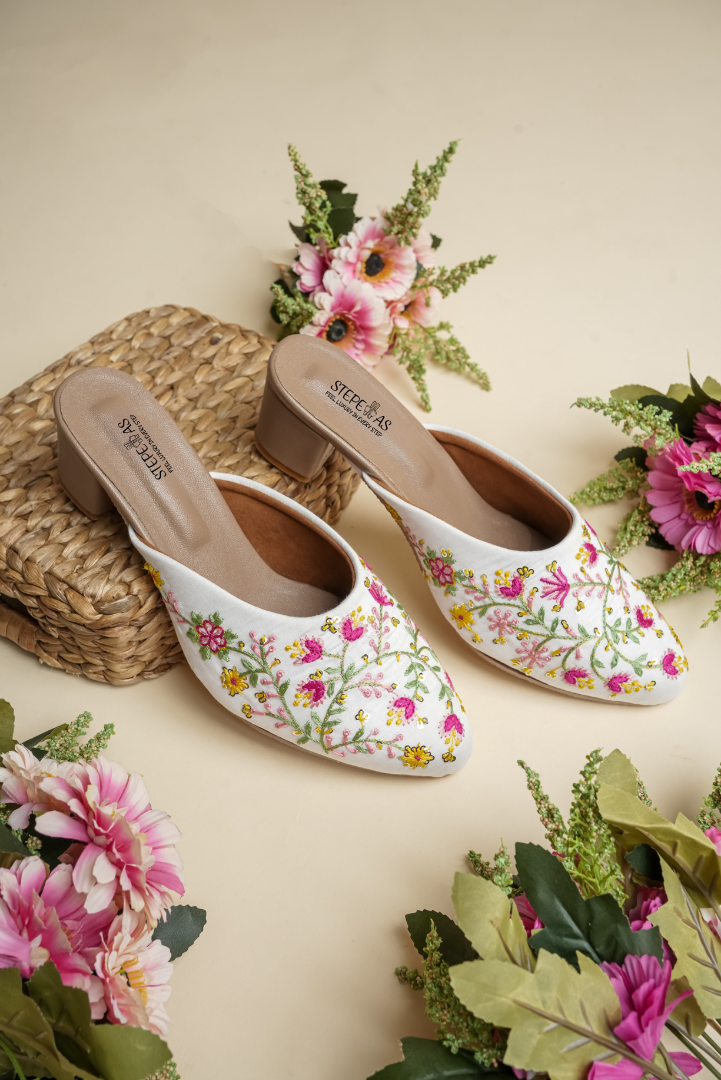 Side view of Stepellas white ethnic heeled mules showing the elegant vine embroidery and stable block heel.