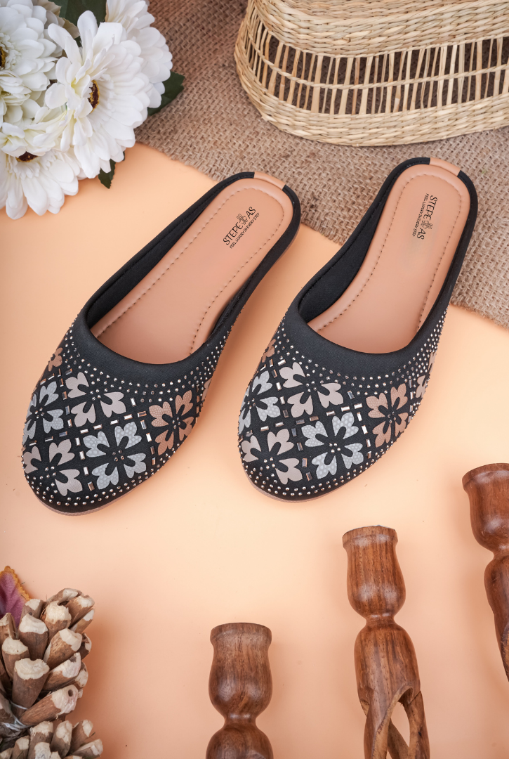 A pair of black Stepellas mules featuring floral embroidery and silver stud embellishments.