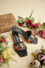 Detailed close-up of the intricate handcrafted floral embroidery on Stepellas black designer sandals.