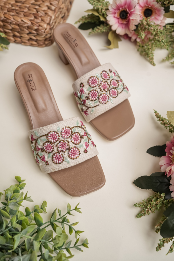 Detailed close-up of the intricate red and blue floral embroidery on Stepellas white designer block heels.