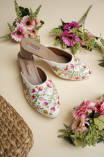 Elegant Stepellas branded white floral heels styled with festive flowers for wedding and bridal fashion.