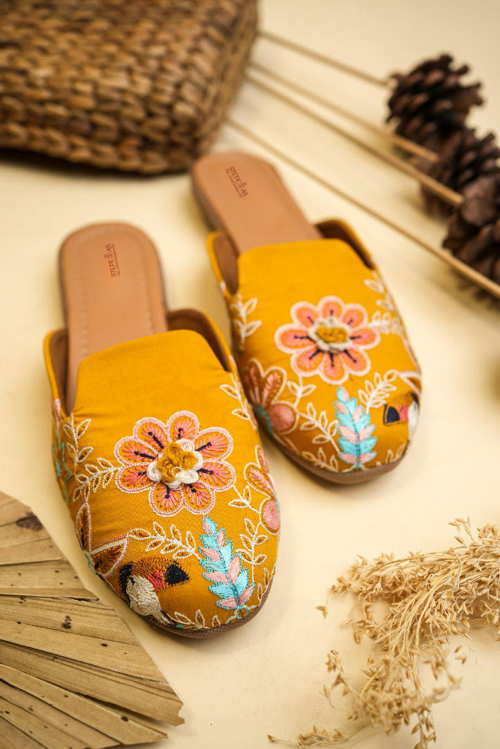 Detailed shot of the handcrafted 3D flowers and intricate embroidery on Stepellas mustard yellow ethnic juttis.
