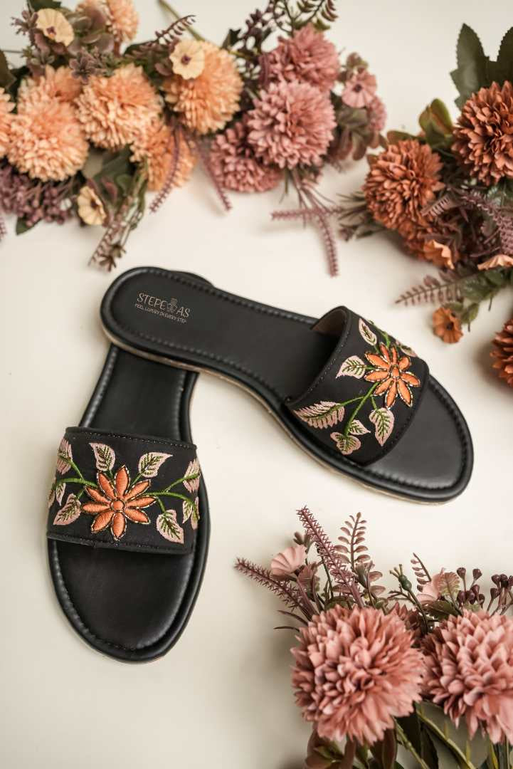 Close-up of the vibrant orange and peach floral threadwork on the black strap of Stepellas ethnic sandals.