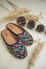Elegant Stepellas black flower embroidery juttis displayed with rustic autumn-themed decor for festive fashion.