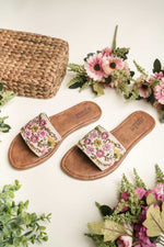 Hand-embroidered white ethnic sandals from Stepellas with pink and yellow flowers on a brown sole.
