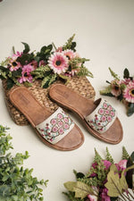 Stepellas white handmade flat chappals with pink beadwork and floral vine embroidery.