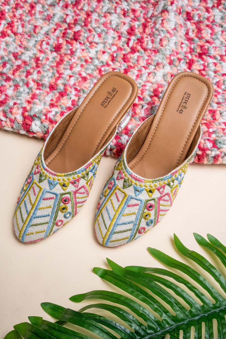 Detailed shot of the multi-color threadwork and foil mirror accents on Stepellas white handcrafted heeled mules.