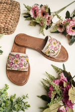 Elegant Stepellas white embroidery sandals displayed with pink daisies, perfect for wedding guest attire.